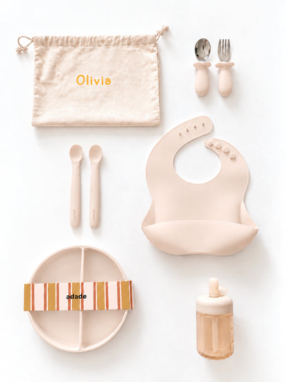 Coffret repas bébé beige avec couverts, bavoir, assiette tasse à paille et pochon personnalisé.