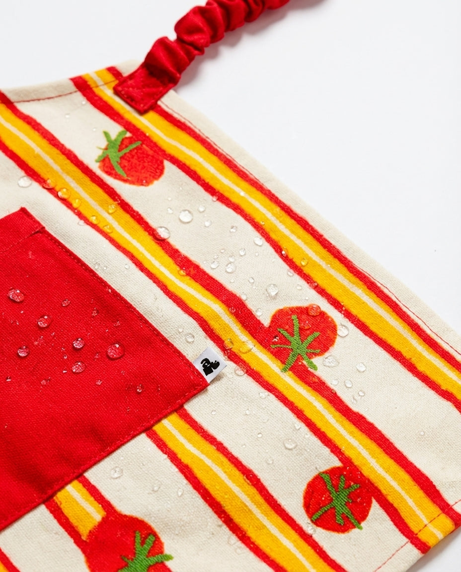 Détail tablier déperlant enfant avec poche rouge et motif tomate