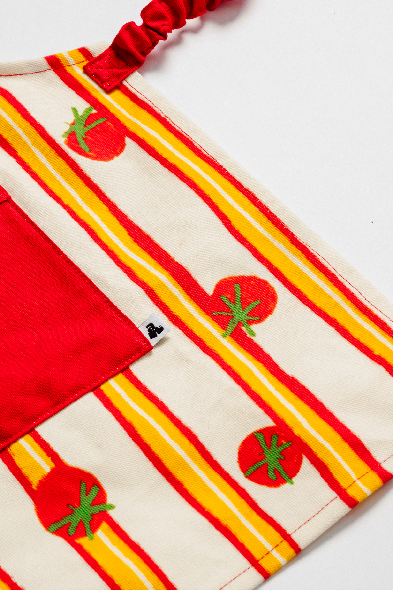 Détail tablier enfant avec poche rouge et motif tomate