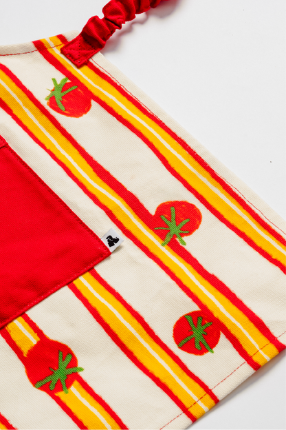 Détail tablier enfant avec poche rouge et motif tomate