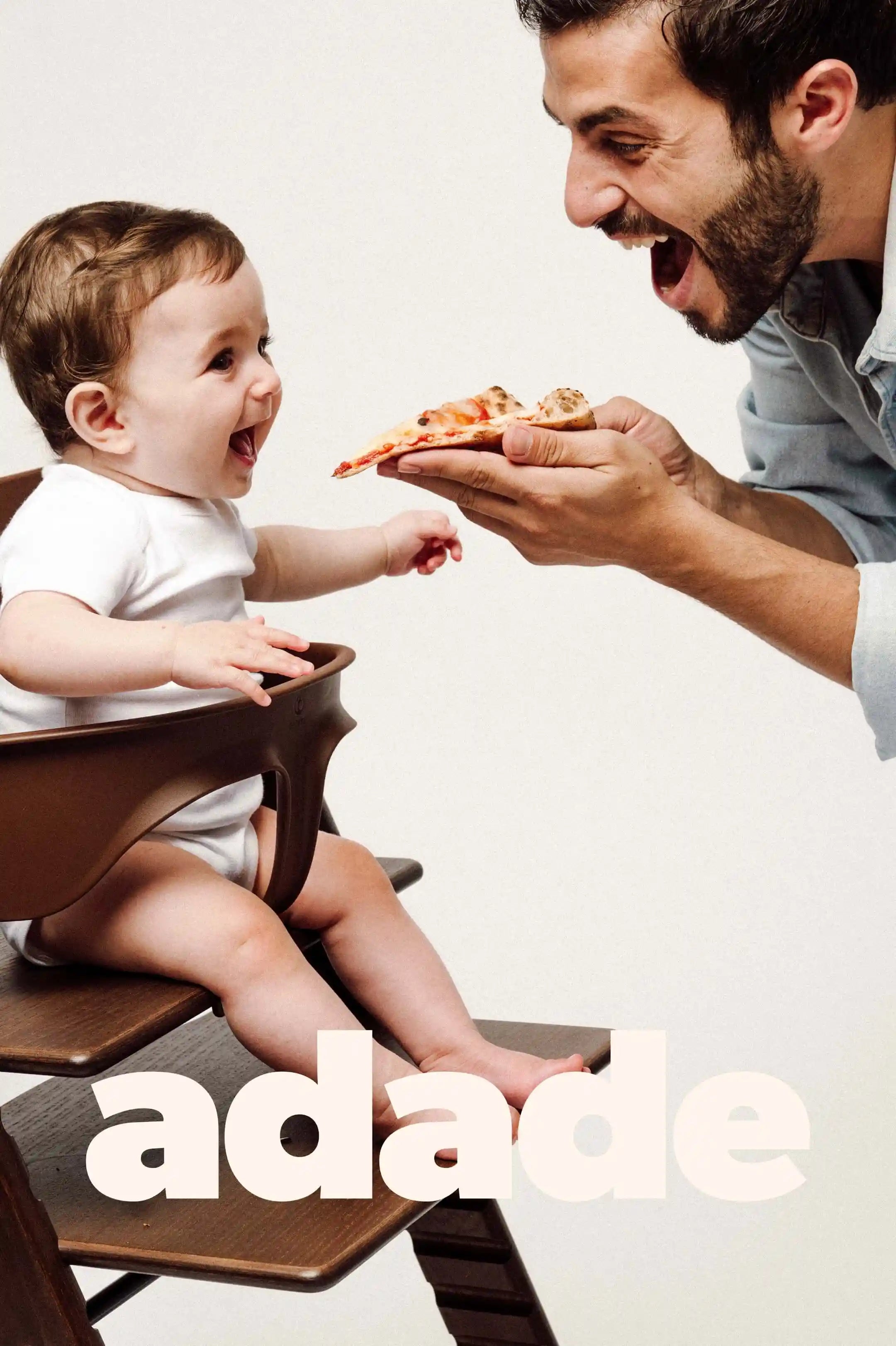 Père donnant à son bébé un morceau d’aliment lors d’un repas pour illustrer une diversification alimentaire sereine, simple et joyeuse.