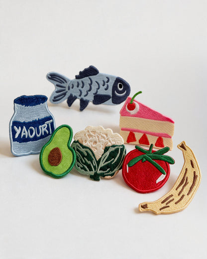 Collection de patchs thermocollants brodés ADADE pour personnaliser les tabliers enfants : tomate, avocat, poisson, banane, chou-fleur, gâteau et yaourt.