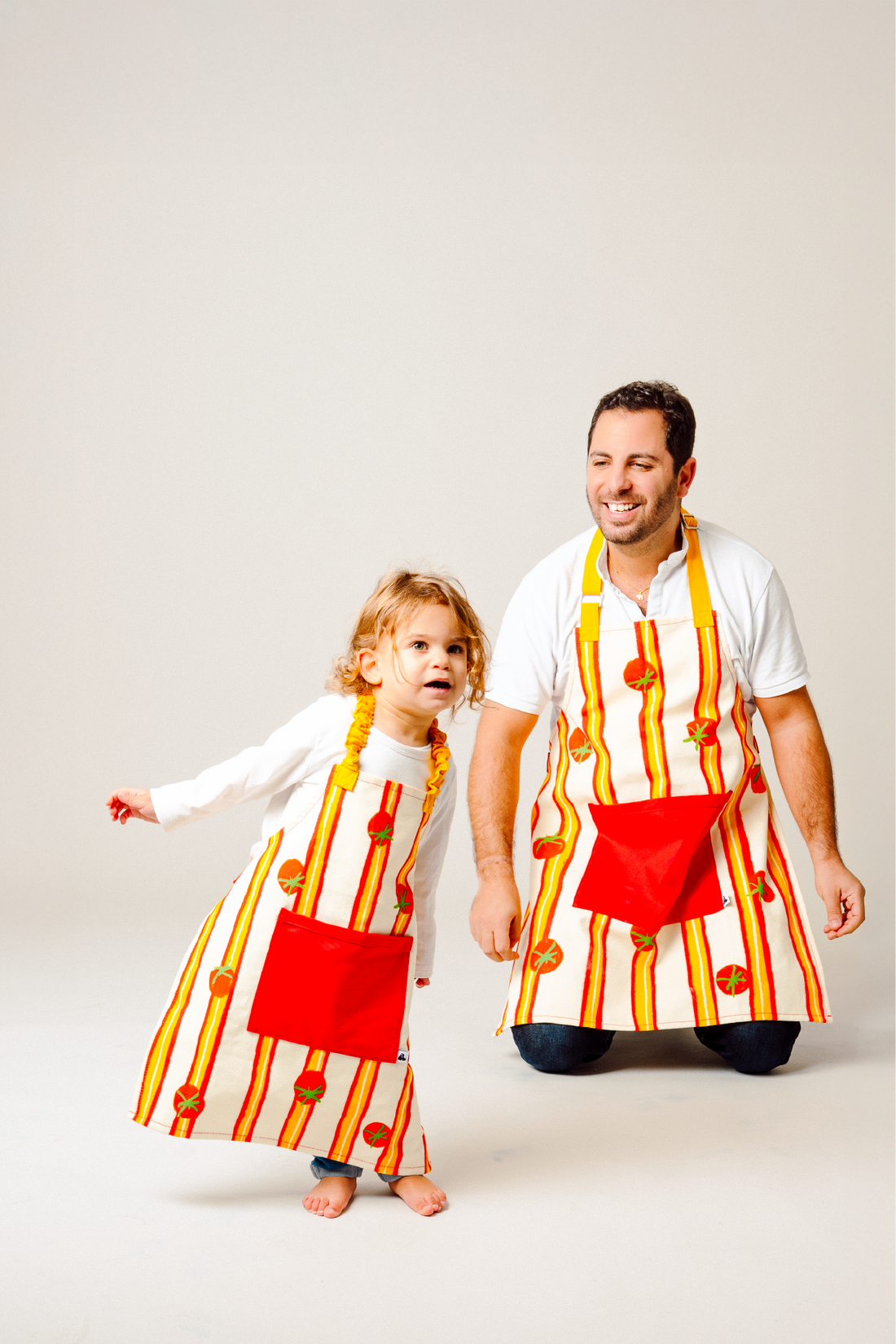Tabliers assortis parent enfant rayés avec motif tomates pour cuisiner en famille
